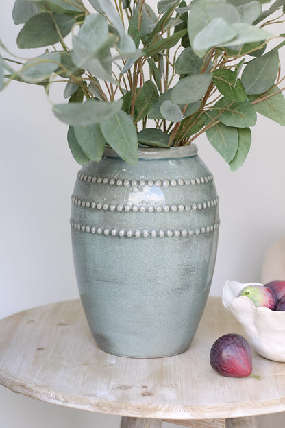 teal ceramic vase filled with faux eucalyptus