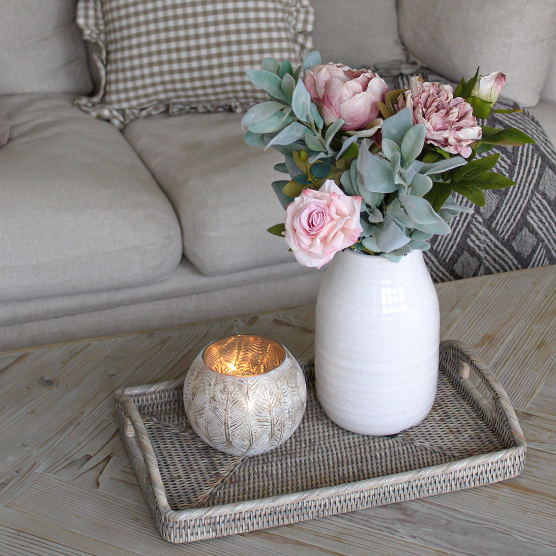 Faux flowers in vase on rattan tray