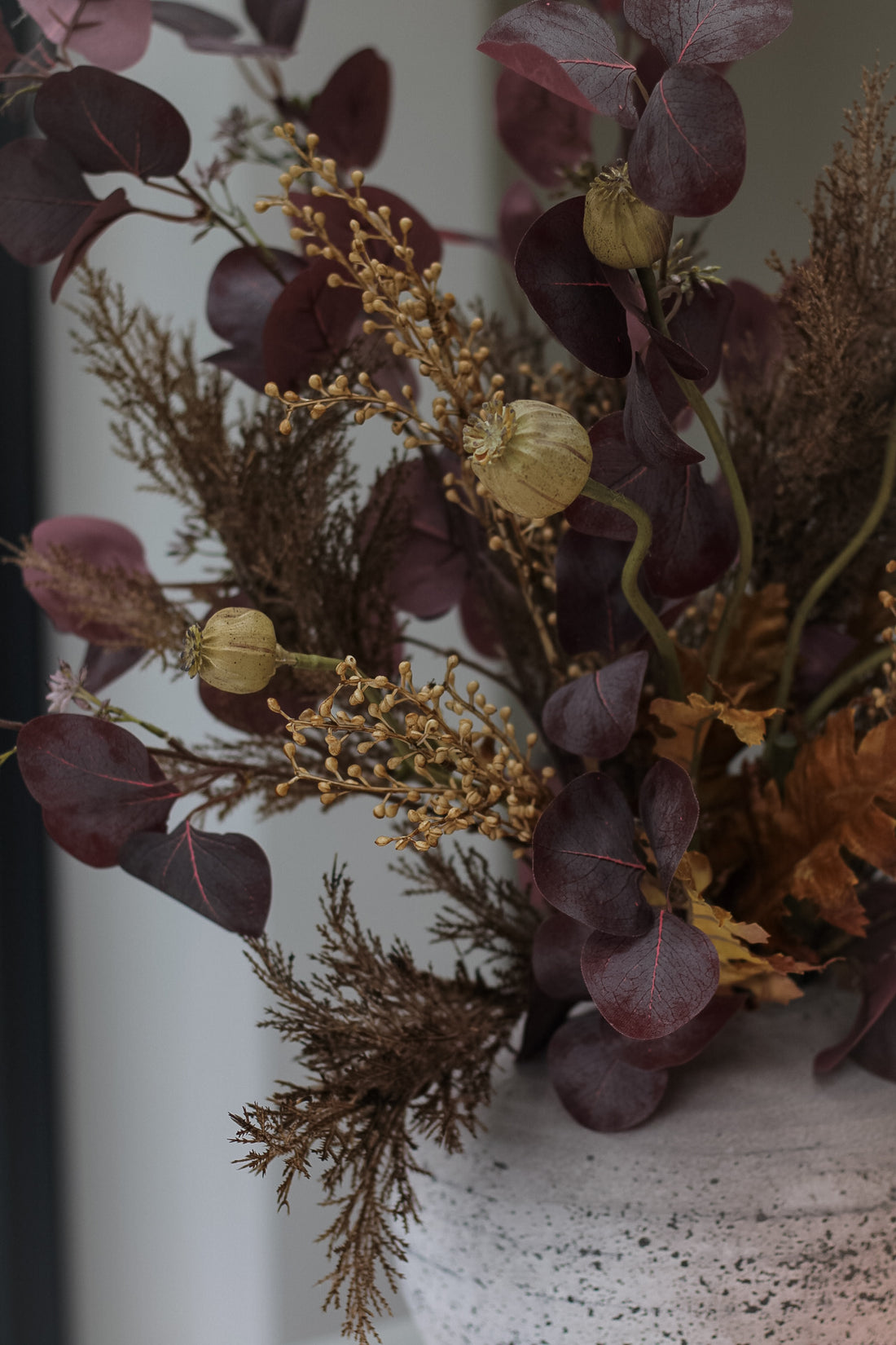 up close of poppy head stems and burgundy eucalyptus