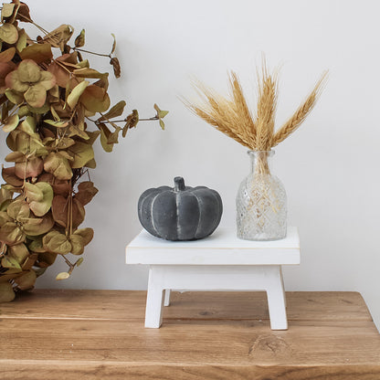 white bench with pumpkin and bud glass vase