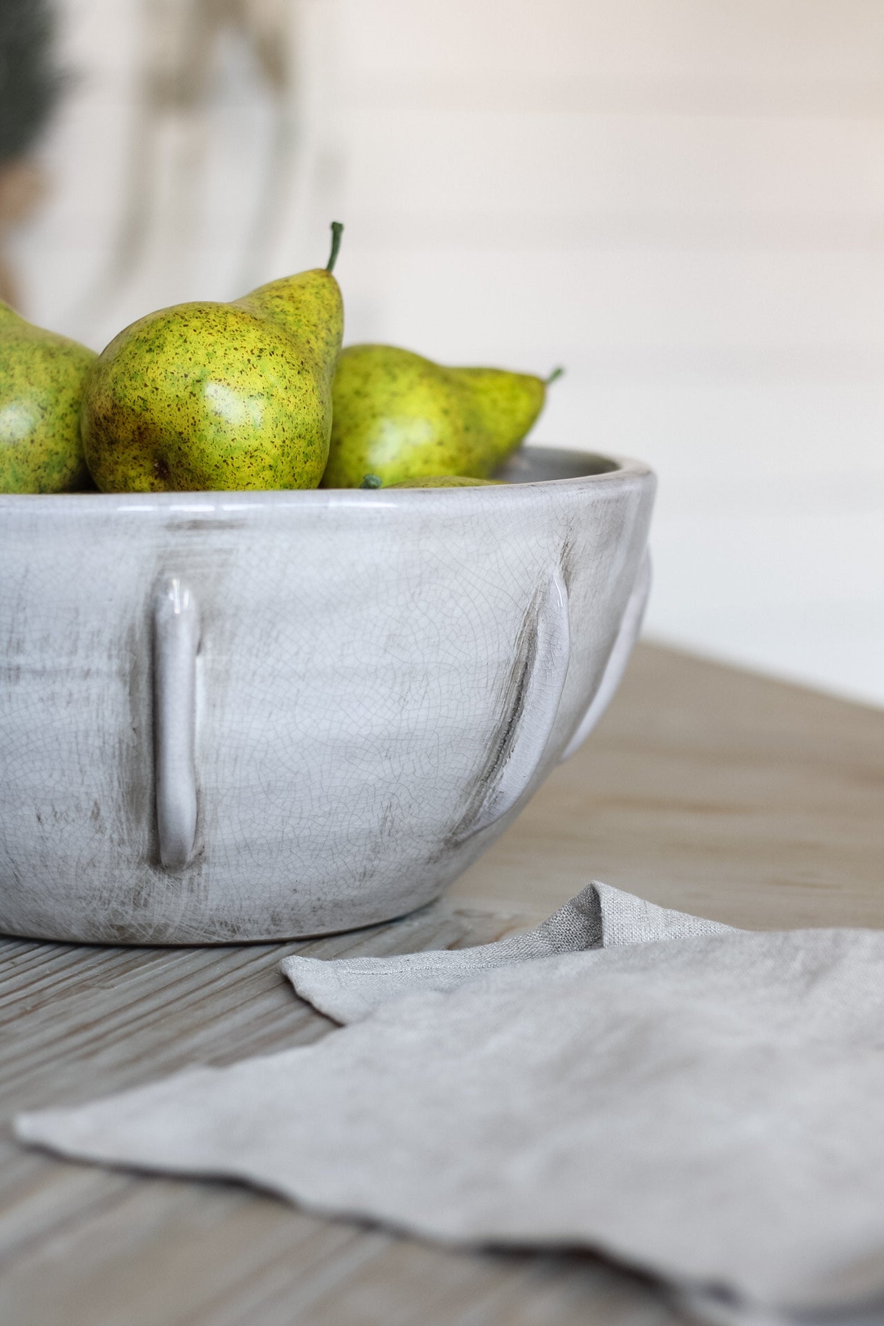 close up of faux green pears in rustic  grey bowl