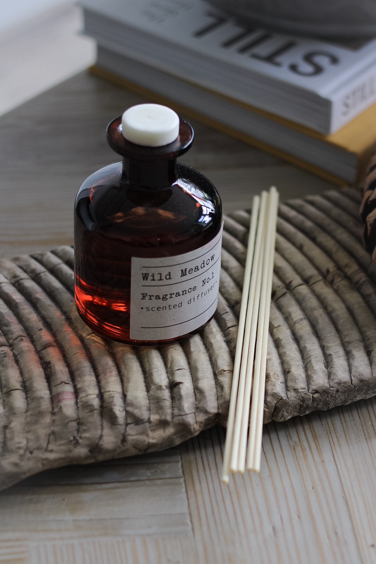 Wild Meadow Reed Diffuser on vintage wooden wash board with reeds lay next to it