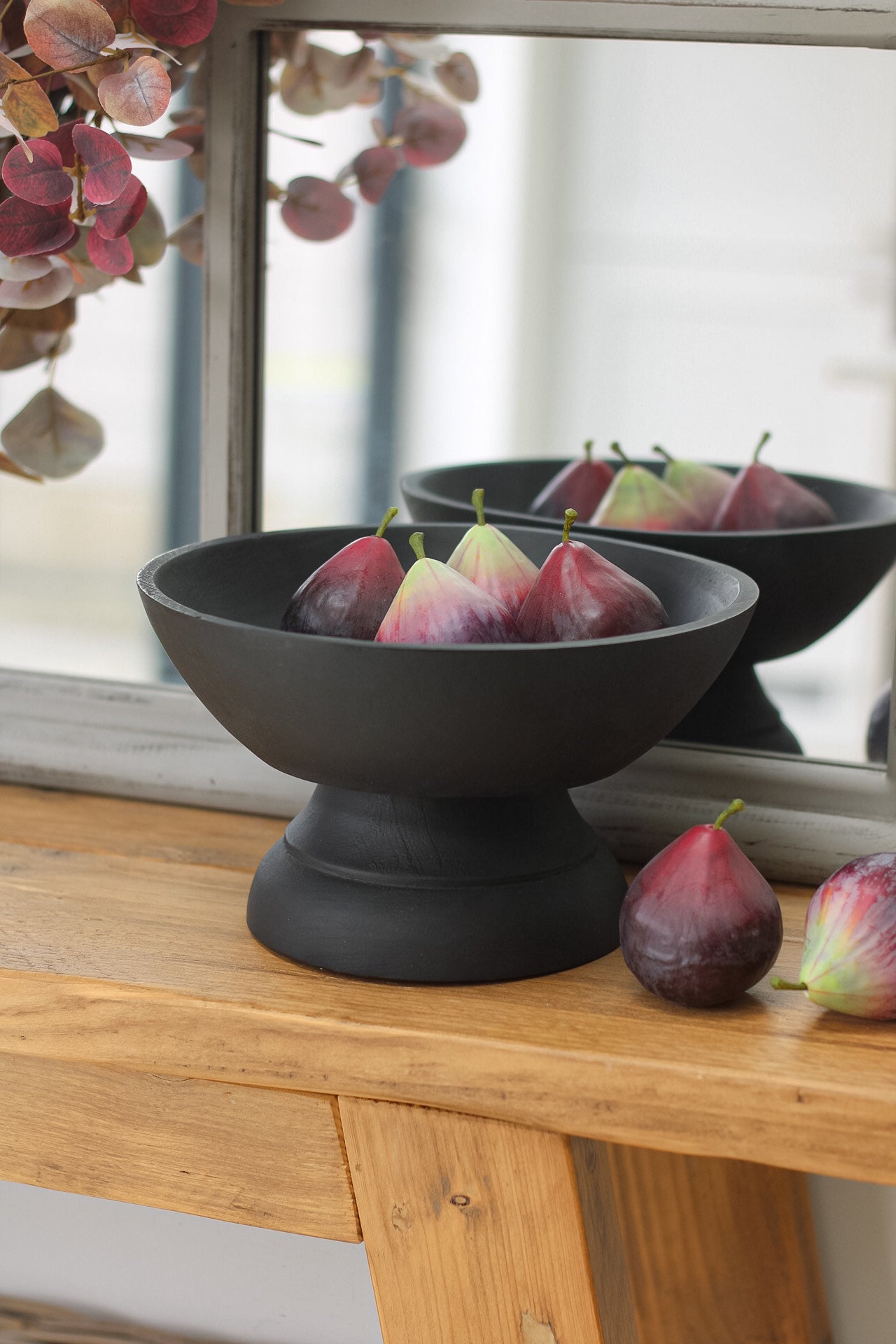 Black mango wood pedestal bowl filled with faux figs