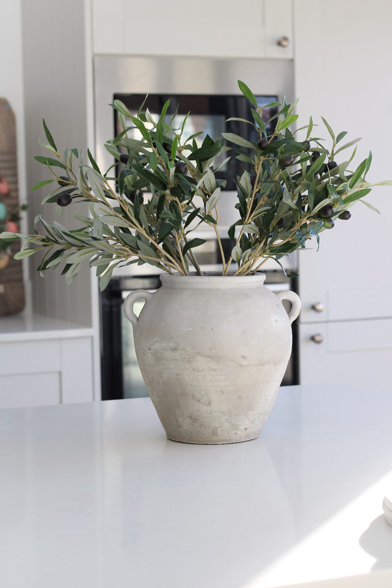 Tall grey olive pot with little handles, pot is filled with faux olive stems