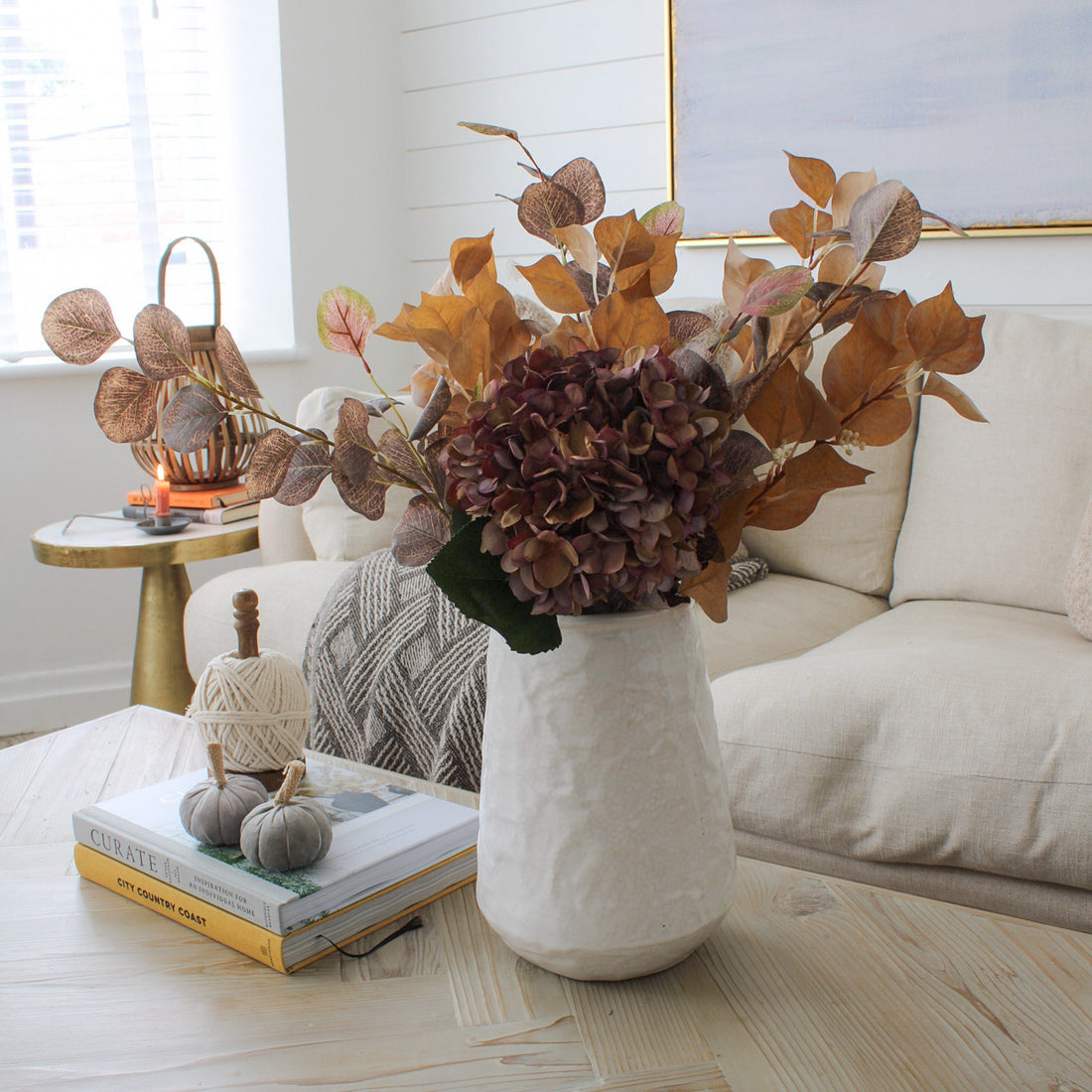 textured white vase filled with faux flowers on coffee table