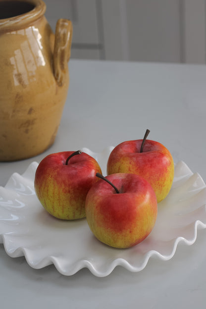 Plate of three realistic faux apples on ceramic ruffled plate