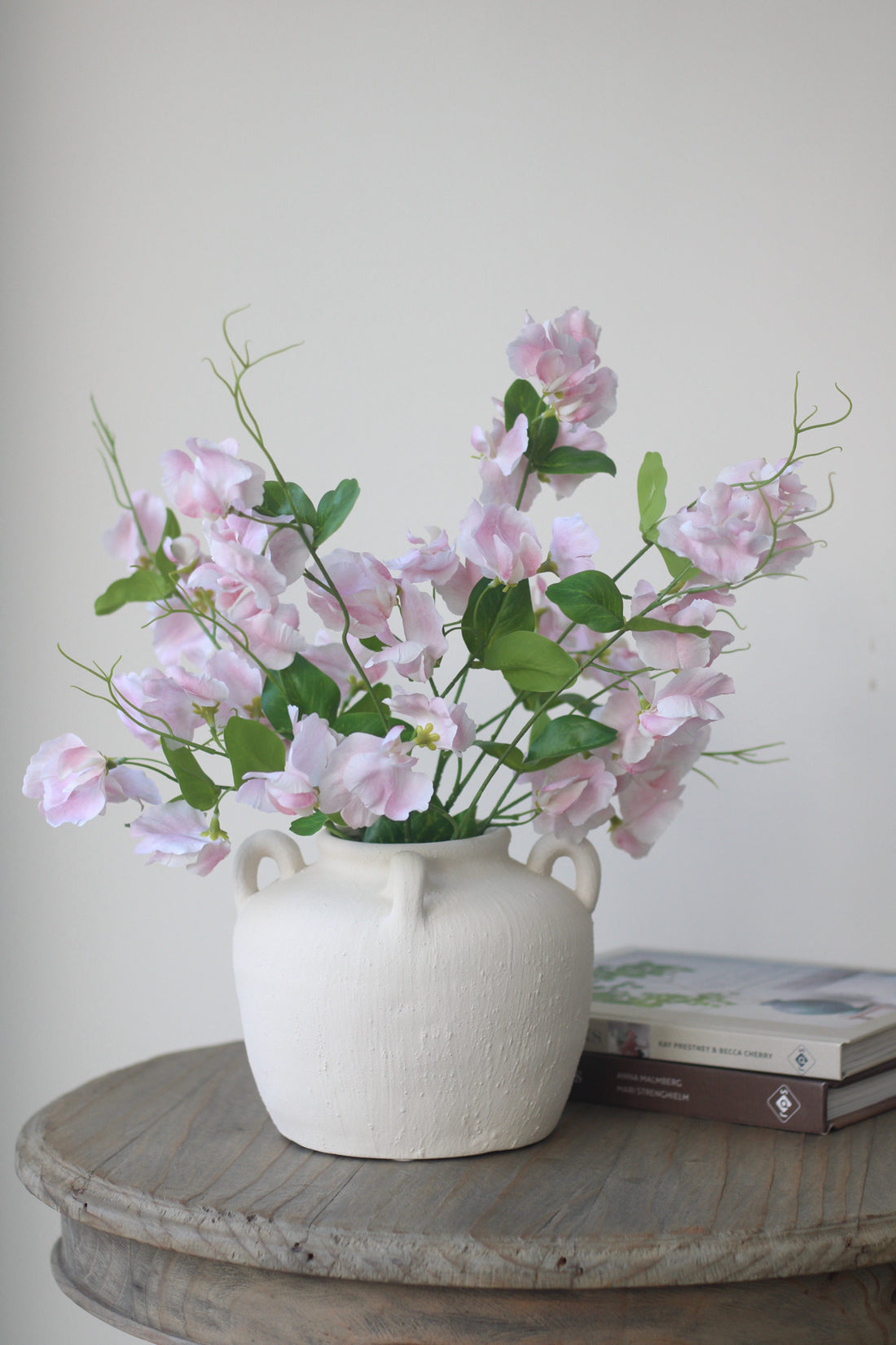 Spring faux flowers.Faux light pink sweetpea stems in white rustic vase.