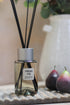 Fresh Fig Reed Diffuser on top of vintage wooden wash board next to a pair of faux figs