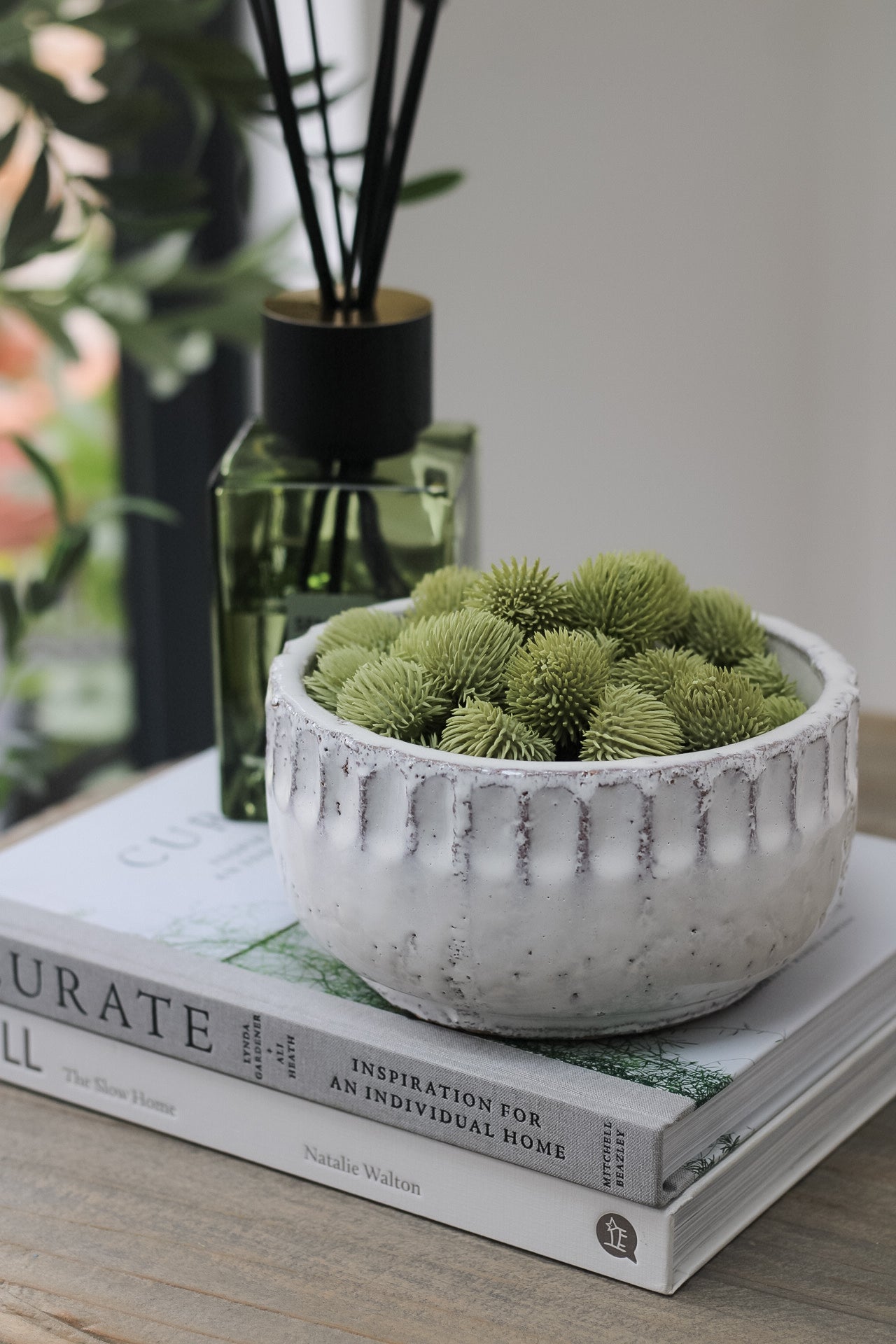 side table styled with luxury sences reed diffuser and ceramic bowl filled with small green organic textured balls