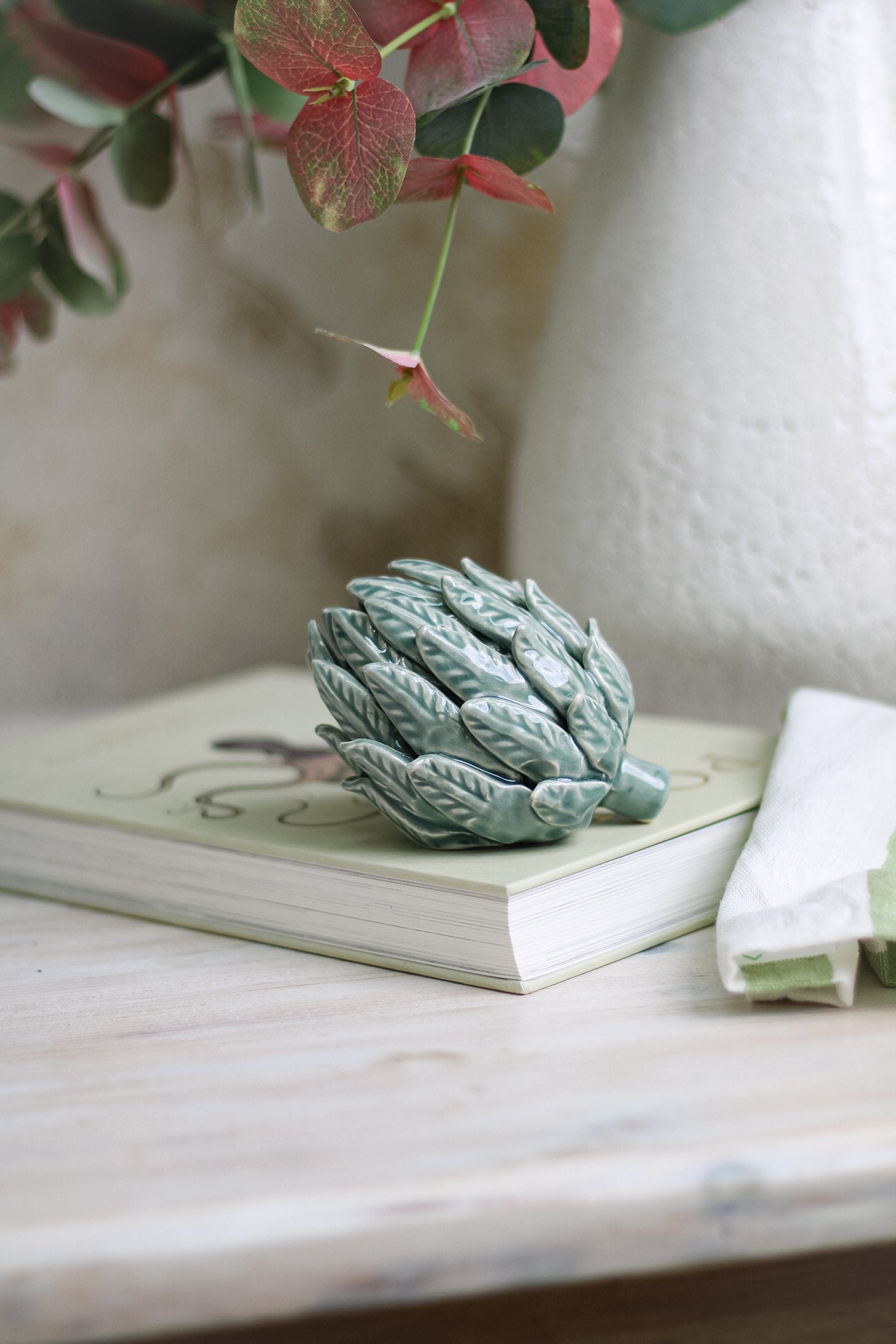 Mint Ceramic Artichoke resting on coffee table book