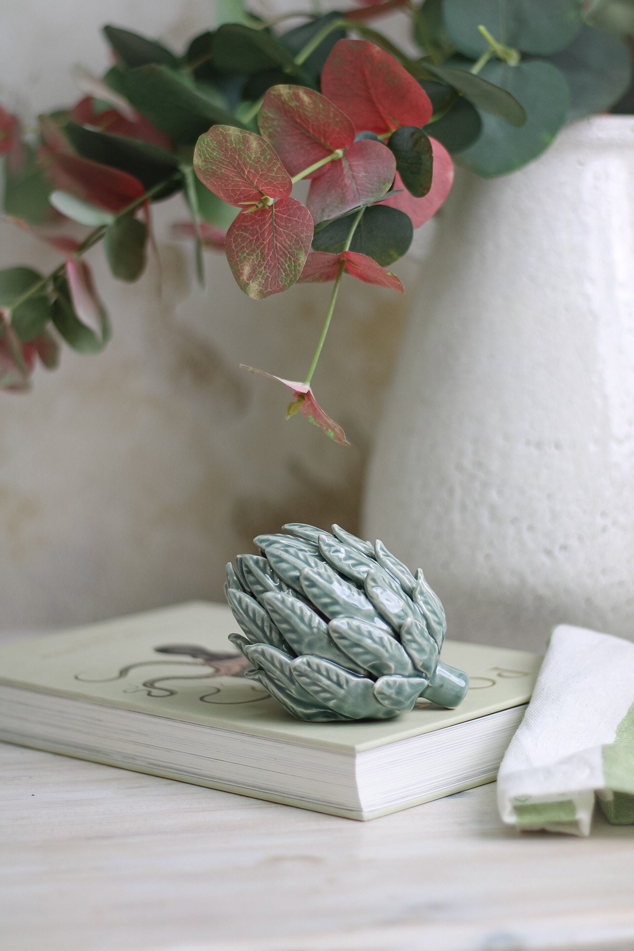 close up of Mint Ceramic Artichoke on coffee table book