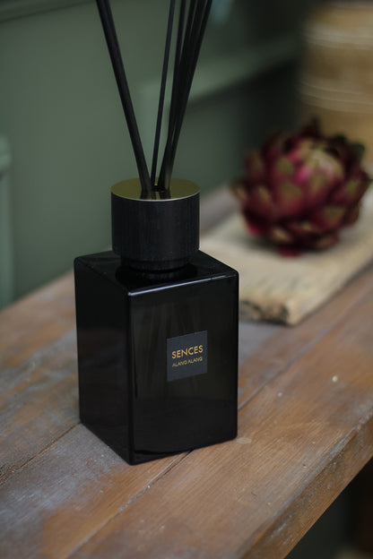 Onyx Sences Alang Alang Reed Diffuser sat on sideboard in front of faux artichoke