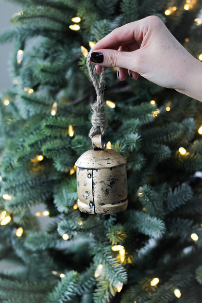 gold bell in front of christmas tree