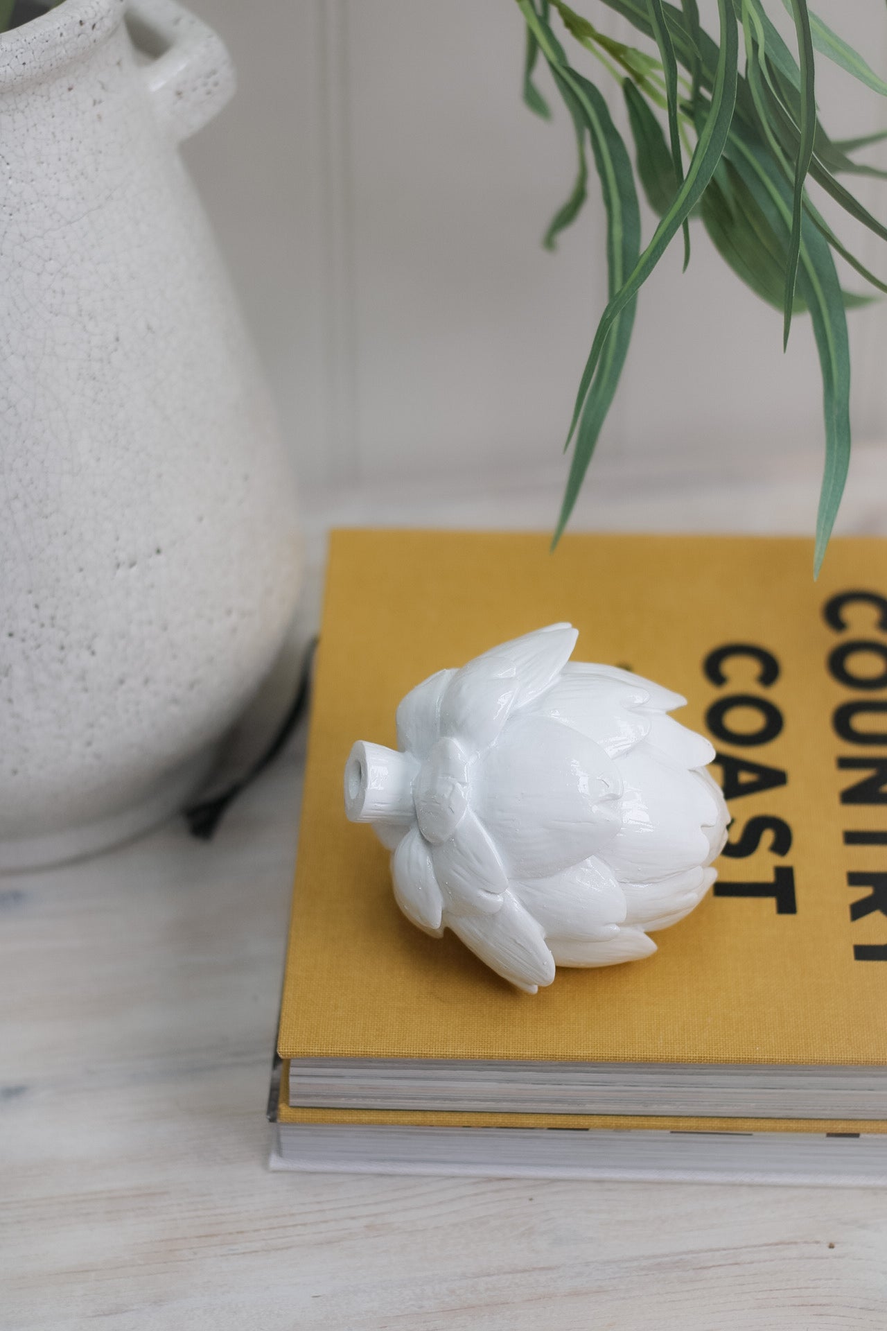 White Artichoke Decoration sat on coffee table book