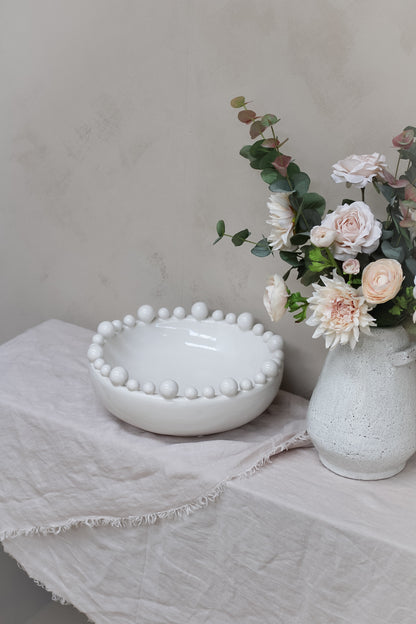 Pink flowers in rustic vase with white ceramic bobbled bowl