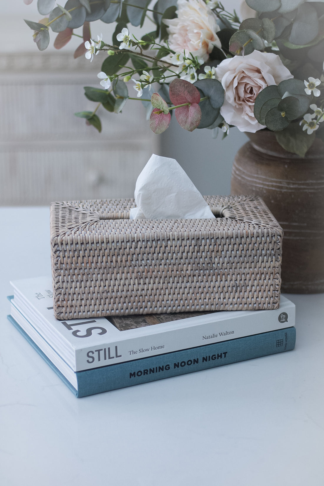 woven rattan rectangular tissue box cover on top of coffee table books.