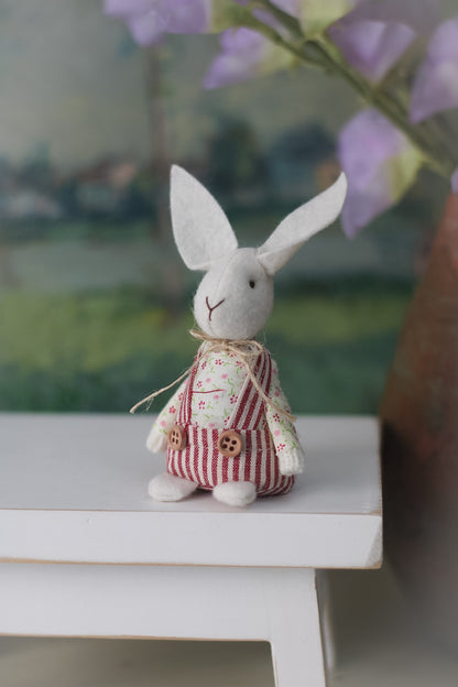 Bunny rabbit in striped dungarees on wooden bench